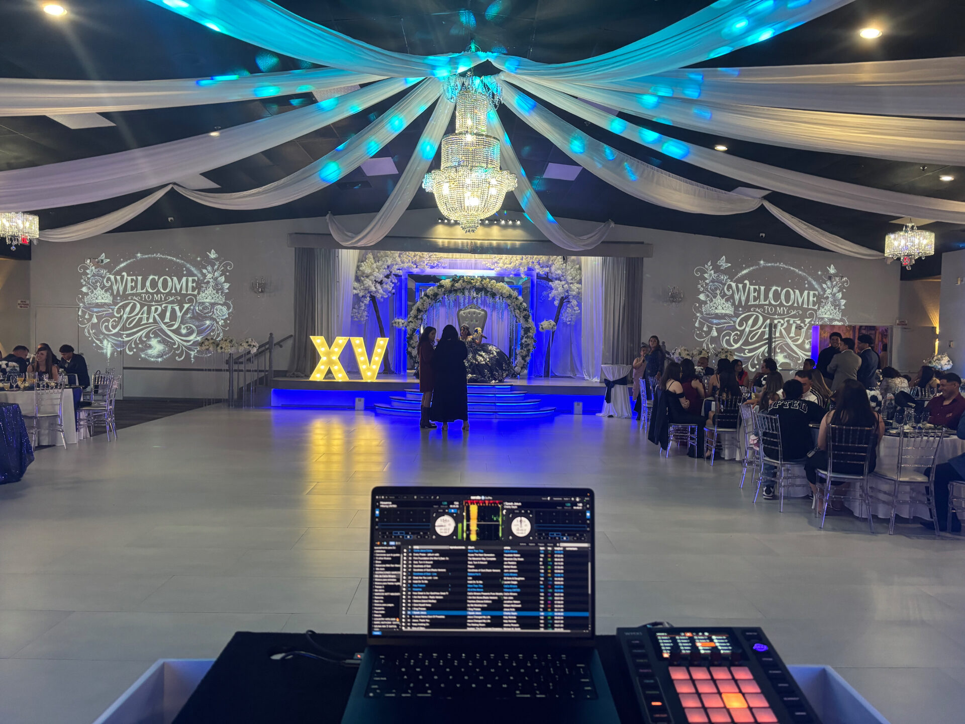 Quinceañera ballroom with chandelier, blue lighting and 'Welcome to my Party' gobo